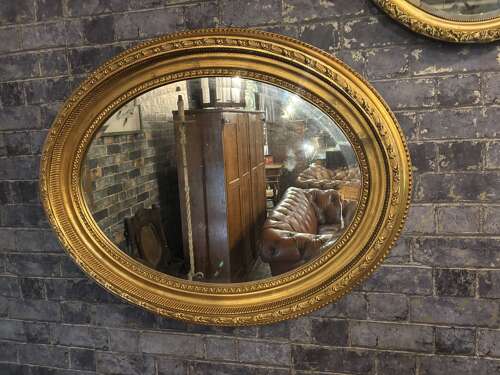 Oval gilt mirror with repeating pattern.