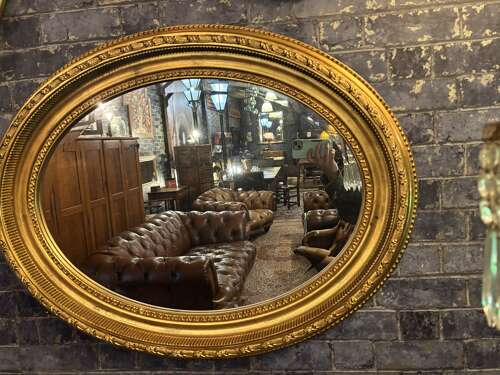Oval gilt mirror with repeating pattern.