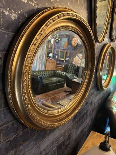Oval gilt mirror with repeating pattern.