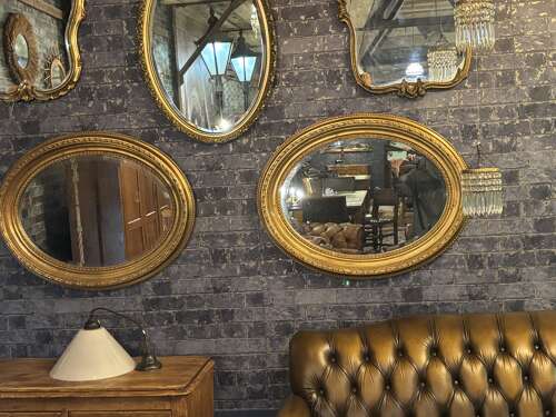 Oval gilt mirror with repeating pattern.